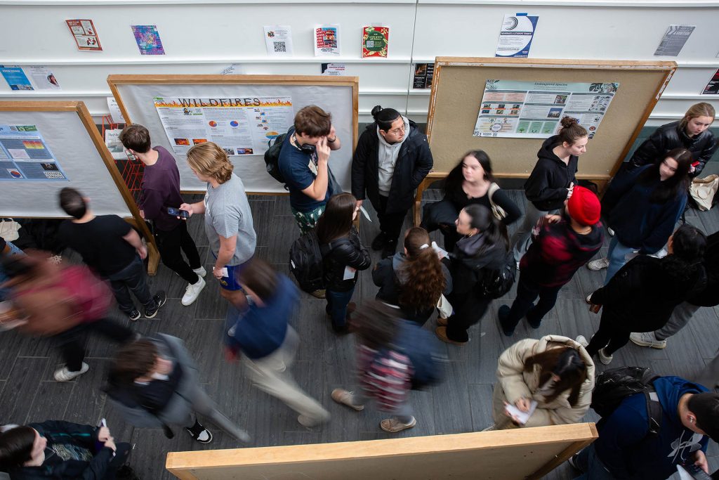 People stream past a research poster session.